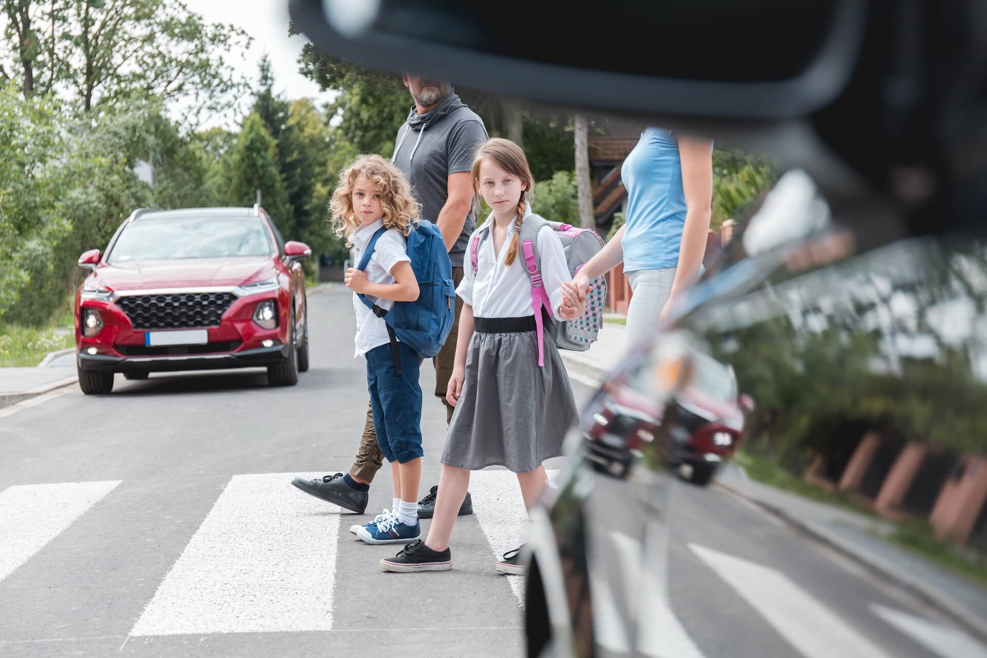 Group of school children goes through the pedestrian crossing in the street, right in front of the car in Baltimore