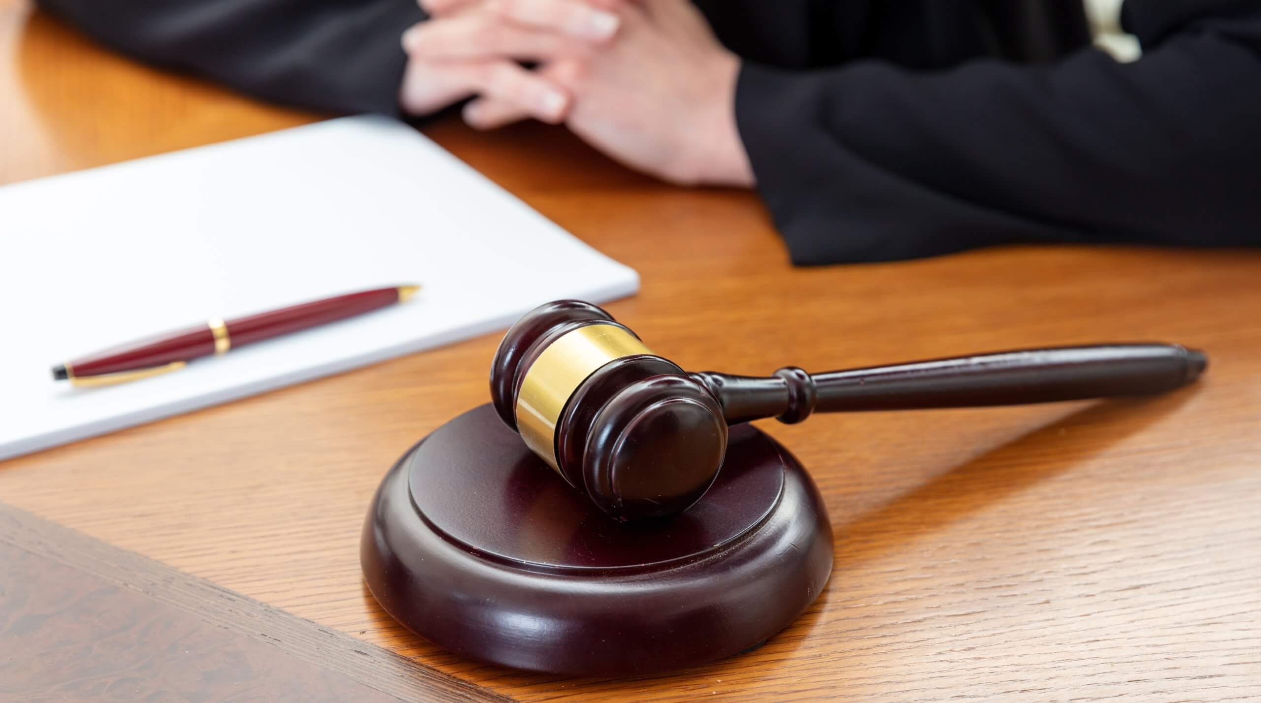 Law courtroom, Judge Bench. Woman sitting, auction gavel and notepad on wooden table, close up.