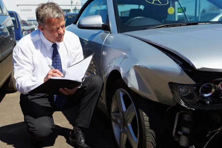 An insurance adjuster surveying a damaged car in Maryland.