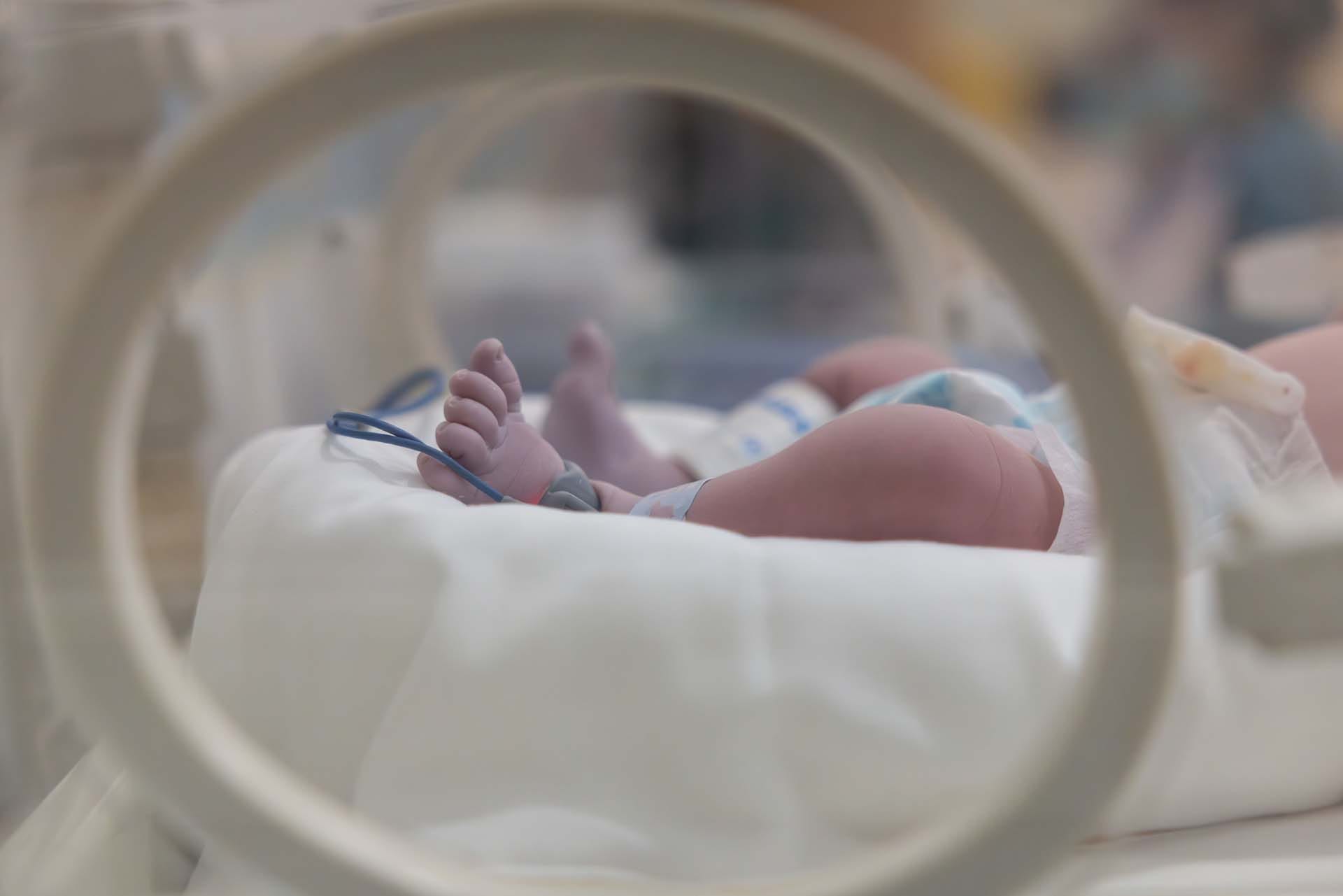 Newborn with a brachial plexus injury in incubator, hospital care scene.