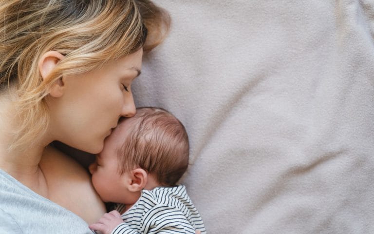 mother and baby with a birth injury laying in bed together while waiting for a birth injury lawyer to call.